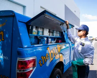 the bugman exterminator standing by the truck