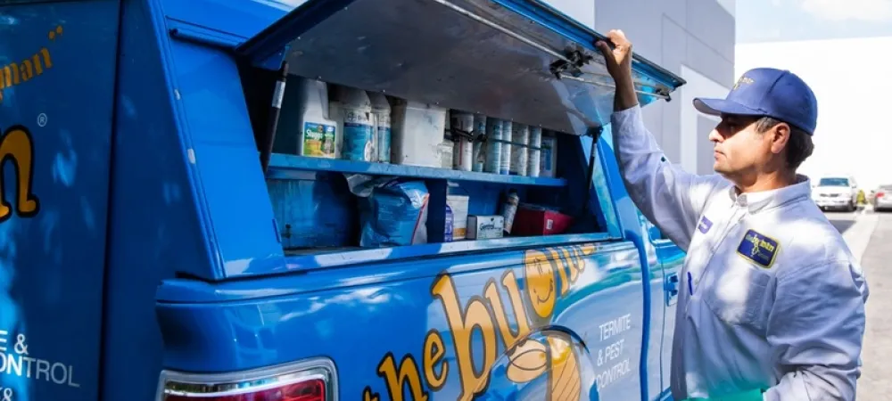 the bugman exterminator standing by the truck
